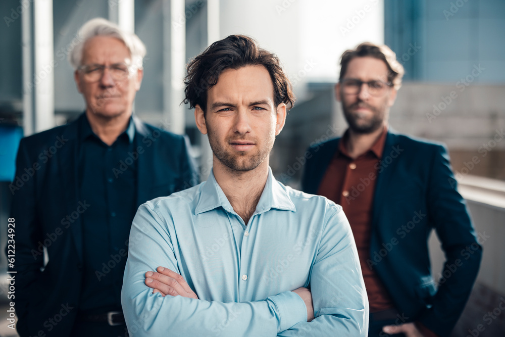 Businessman with arms crossed standing in front of colleagues Businessman with arms crossed standing in front of colleagues