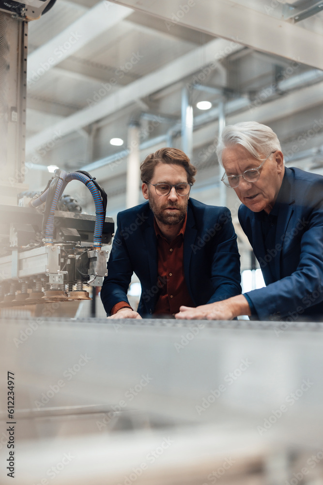 Businessmen examining and operating machinery in factory Businessmen examining and operating machinery in factory
