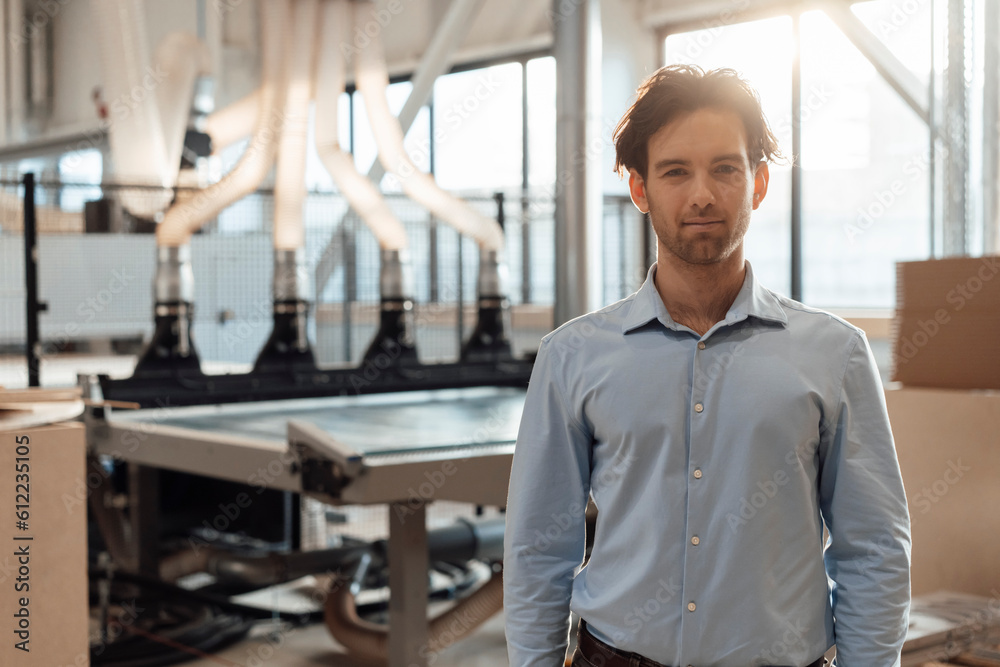 Smiling young businessman standing in industry Smiling young businessman standing in industry