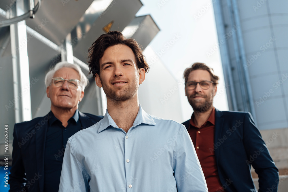 Young businessman with colleagues standing in front of machinery Young businessman with colleagues standing in front of machinery