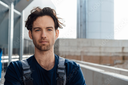 Young man in dungarees at industrial building