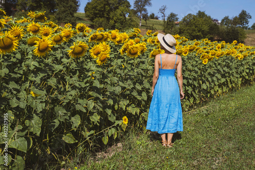 Woman standing near sunflowers in field at sunny day photo