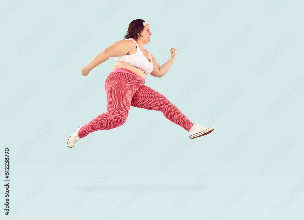 Full length photo of young fat overweight woman wearing sportswear jumping and hurrying to the gym to do exercises isolated on studio blue background. Workout sport, fitness and body positive concept