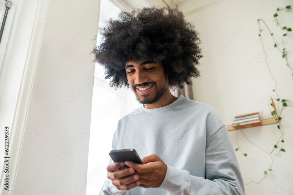Smiling man using smart phone at home Smiling man using smart phone at home