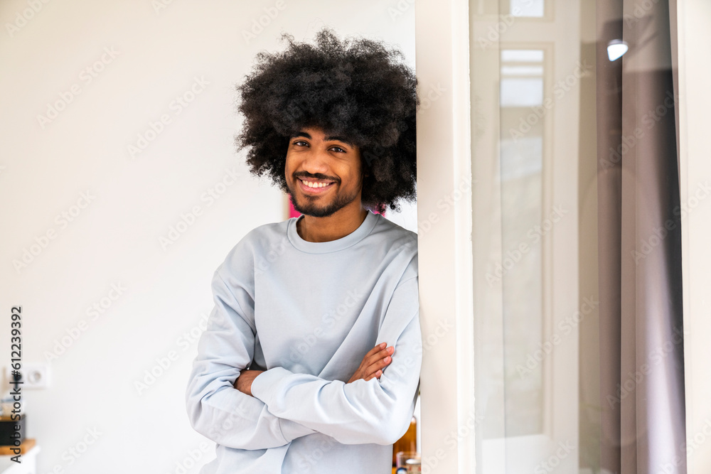 Smiling man with arms crossed leaning on door at home Smiling man with arms crossed leaning on door at home