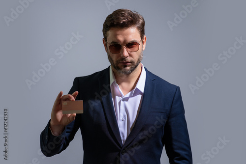 Handsome man holding credit card. Middle aged man in suit with credit card isolated on gray studio background. Credit bank card concept. Businessman in business suit pay by credit card.