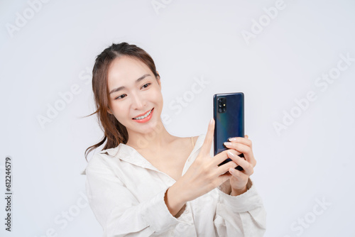 Asian women's casual outfits and natural makeup take a photo with smartphones. White background. 