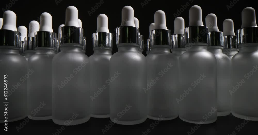 Many number of empty bottles with pipettes on black background. Bottles designed to store cosmetics and medicines Many number of empty bottles with pipettes on black background. Bottles designed to store cosmetics and medicines