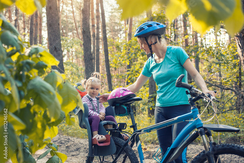 mom and baby ride a bike in a summer pine forest