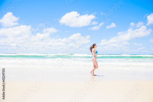 青い空と海の前を歩くビキニの白人女性
