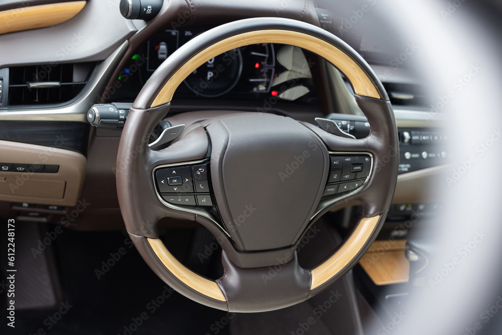 Car steering wheel. Brown leather dashboard, climate control, speedometer, display, wood decoration. Expensive car interior with steering wheel