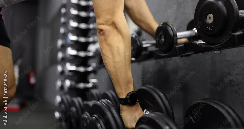 Male hands take dumbbells for bodybuilding in gym. Closeup sportsman hands taking weight lifting in sport club Male hands take dumbbells for bodybuilding in gym. Closeup sportsman hands taking weight lifting in sport club