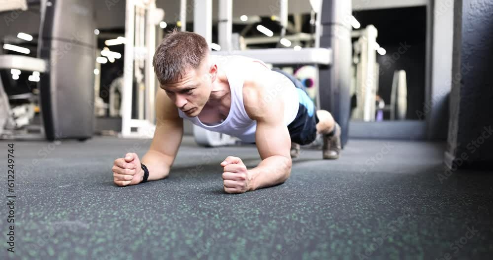 Male athlete stands on board on floor in gym. Sports endurance and motivation Male athlete stands on board on floor in gym. Sports endurance and motivation