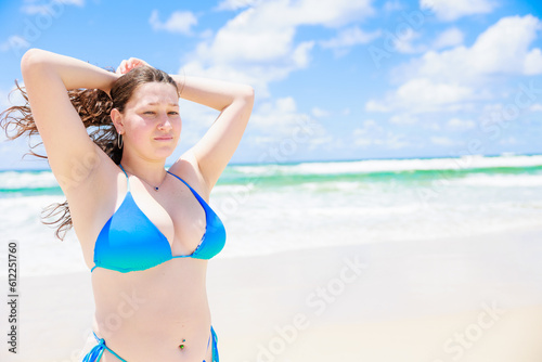 髪の毛を束ねる水着姿の白人女性