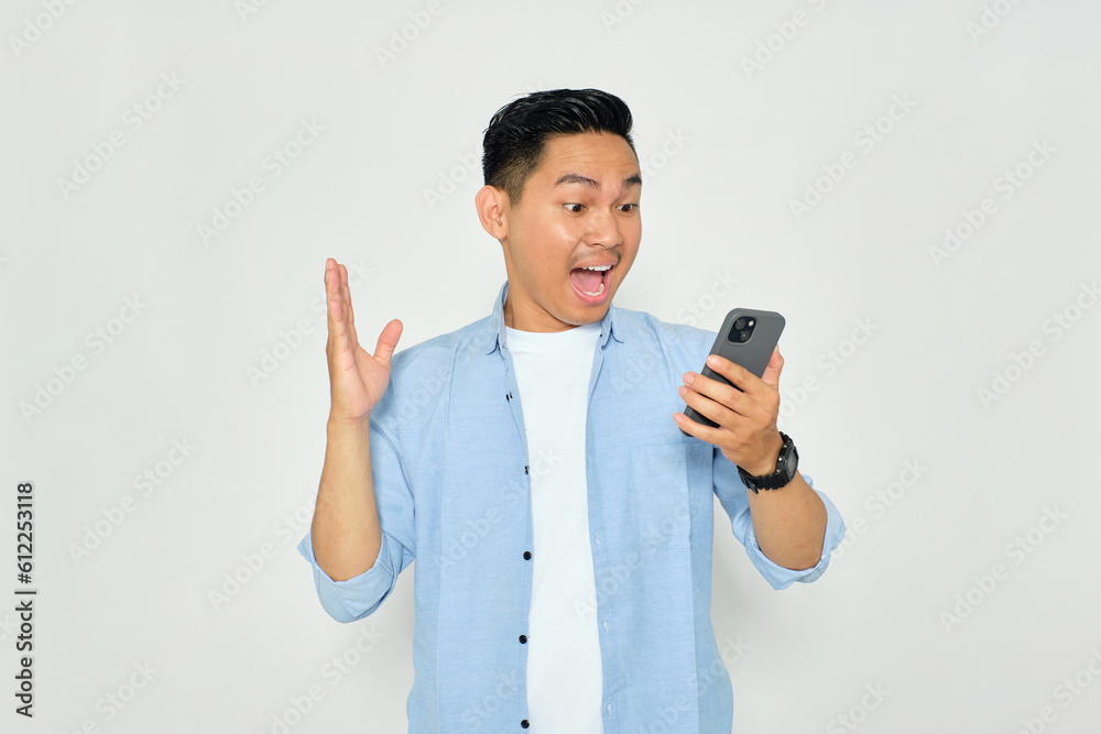 Portrait of handsome young Asian man in casual clothes looking at cellphone screen with shocked expression, reading good news isolated on white background Portrait of handsome young Asian man in casual clothes looking at cellphone screen with shocked expression, reading good news isolated on white background