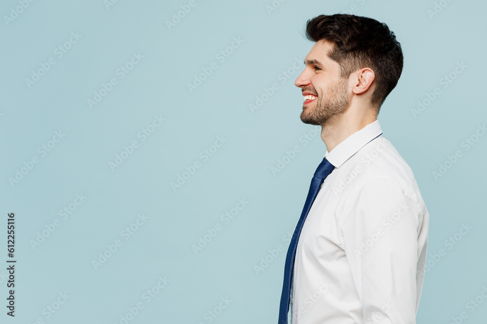 Side view close up smiling happy young successful employee business man corporate lawyer wears classic formal shirt tie work in office isolated on plain pastel light blue background studio portrait. Side view close up smiling happy young successful employee business man corporate lawyer wears classic formal shirt tie work in office isolated on plain pastel light blue background studio portrait.