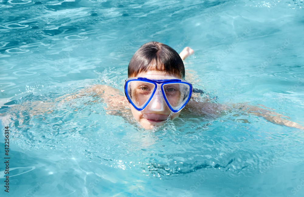 Close up portrait of teen boy in water mask swimming in swimming pool. Summer holiday concept.