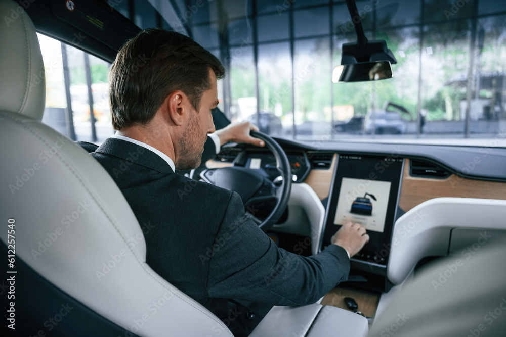 Rear view. Businessman in suit is driving his electric car Rear view. Businessman in suit is driving his electric car
