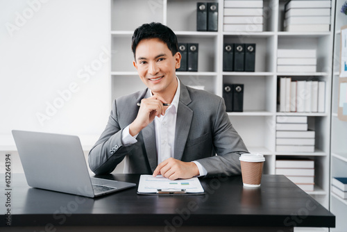 Male businessmen sitting at the desk, looking to camera.