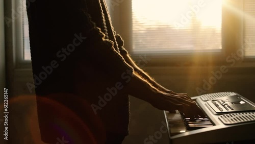 man playing synthesizer at home at sunset, music learning concept photo