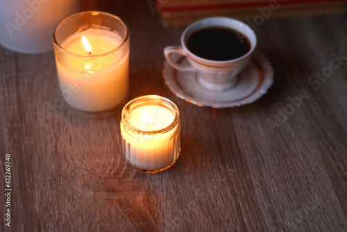 Cup of tea or coffee, plate of cookies, books, e-reader, pencil and lit candles on the table. Selective focus. © jelena990