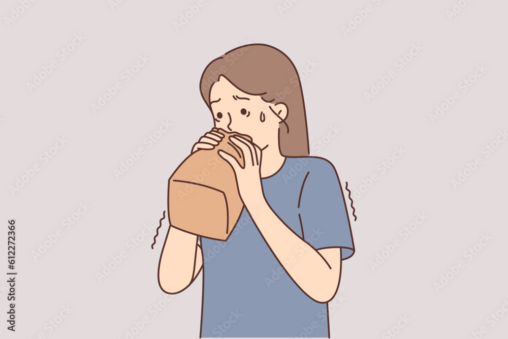 Nervous girl breathes into paper bag trying to cope with panic caused by psychological disorder Nervous girl breathes into paper bag trying to cope with panic caused by psychological disorder