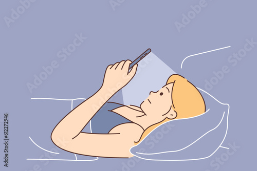 Woman suffers from mobile phone addiction using gadget lying in bed and refusing to sleep