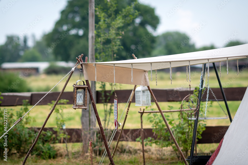 A tent in the field with a lantern and a wooden fence.