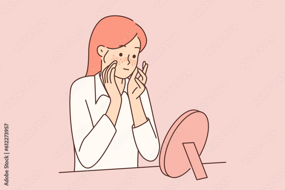 Teenager girl with freckles on face looks in mirror, studying rash or pimples that have appeared Teenager girl with freckles on face looks in mirror, studying rash or pimples that have appeared