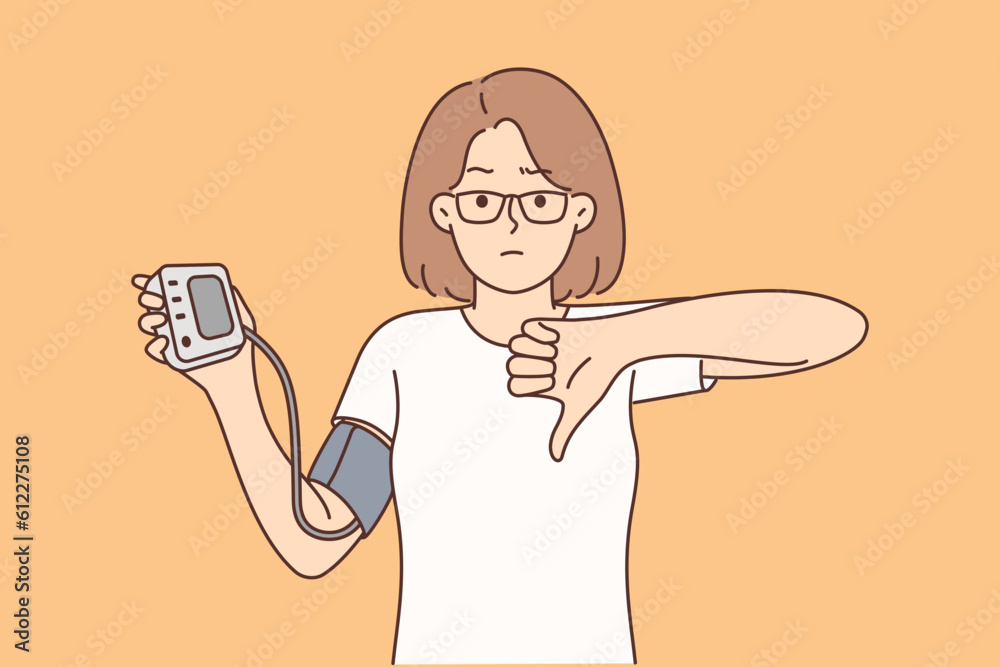 Woman holding tonometer to check cardio health and heart disease shows thumb down