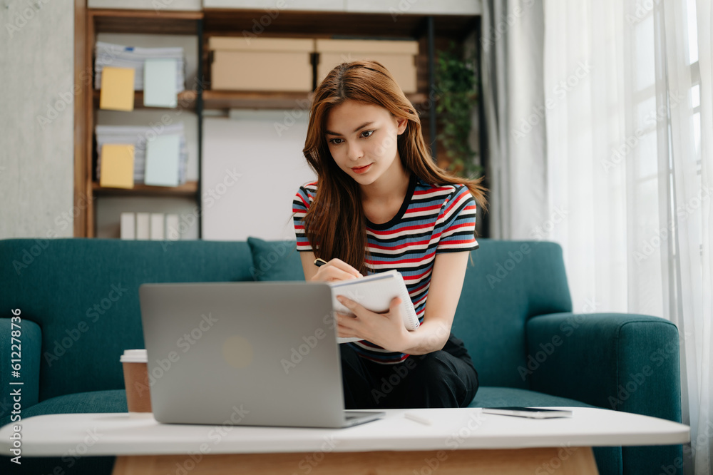 Young beautiful woman using laptop and tablet while sitting at her working place. Concentrated at work. in living room on the sofa at home office. Young beautiful woman using laptop and tablet while sitting at her working place. Concentrated at work. in living room on the sofa at home office.