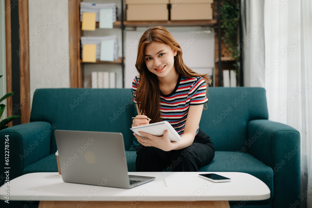 Young beautiful woman using laptop and tablet while sitting at her working place. Concentrated at work. in living room on the sofa at home office. Young beautiful woman using laptop and tablet while sitting at her working place. Concentrated at work. in living room on the sofa at home office.
