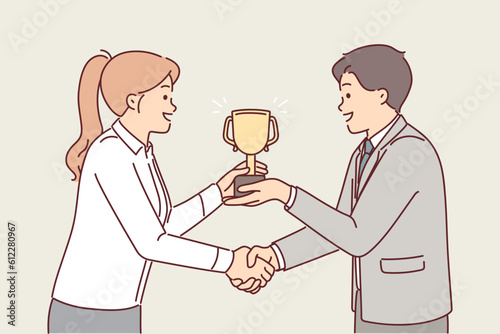 Boss presents cup to subordinate in recognition of achievement and shakes hands to motivate