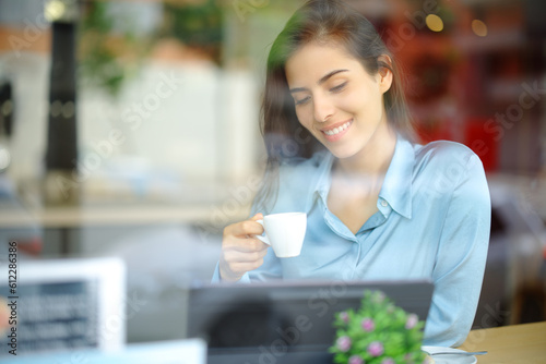 Happy woman drinking in a bar using tablet