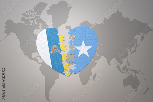 puzzle heart with the national flag of somalia and canary islands on a world map background.Concept.