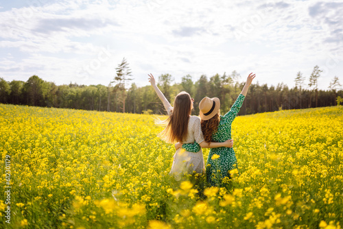 Two beautiful woman in the blooming field. Nature, vacation, relax and lifestyle. Summer landscape.