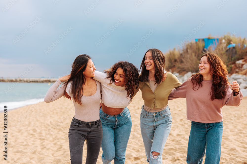 Four happy young women laughing while walking at beach. Four happy young women laughing while walking at beach.