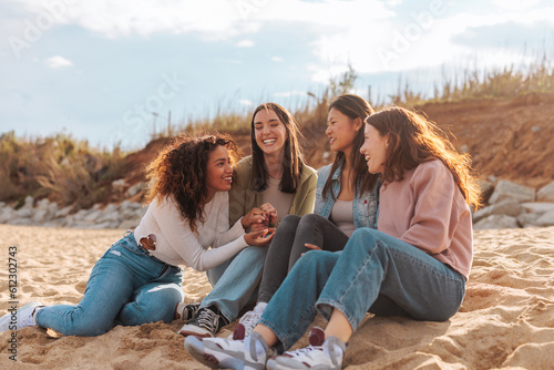 Four diverse young women gossiping on beach