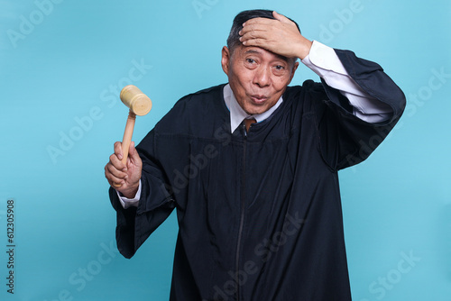 Asian senior judge man has realized something and intending the solution isolated on blue background 