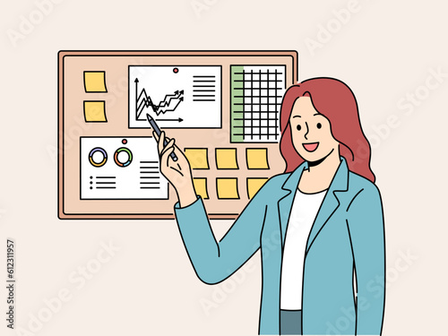 Businesswoman demonstrates financial graphs and charts pinned on cork board in office. Businesswoman boasts about growth of company income and number of clients that bring income to business.