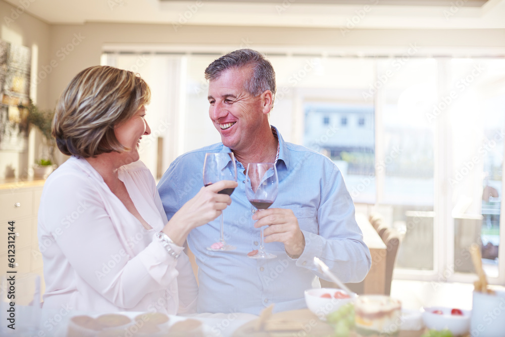 Smiling couple toasting red wine glasses in kitchen