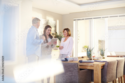 Interior designer using digital tablet in consultation couple in dining room