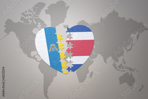 puzzle heart with the national flag of costa rica and canary islands on a world map background.Concept.
