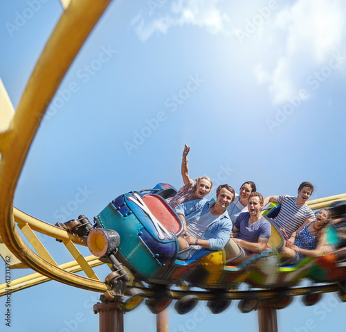 Cheering friends riding roller coaster at amusement park photo