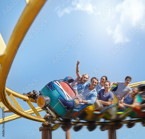 Фотография Cheering friends riding roller coaster at amusement park