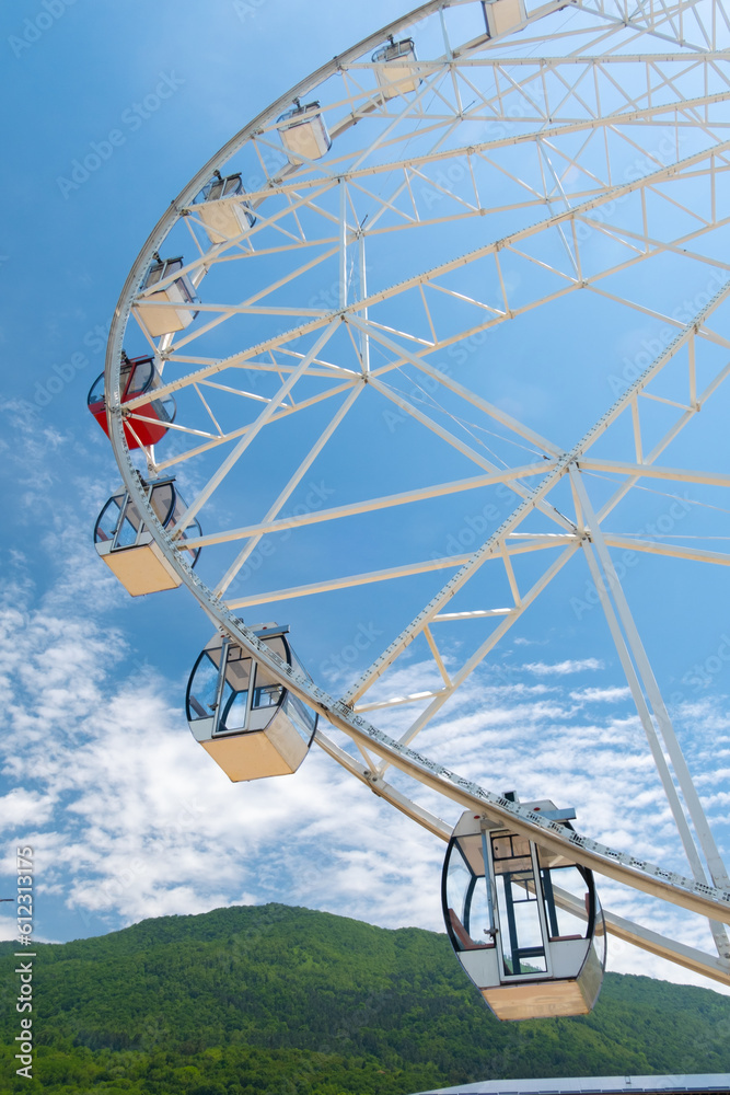 A tall Ferris wheel in the park against a blue sky
