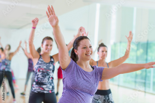 Smiling woman with arms raised in exercise class