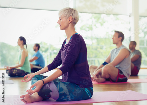 Serene woman in lotus position in yoga class