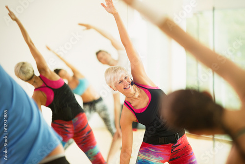 Smiling fitness instructor leading aerobics class stretching arms