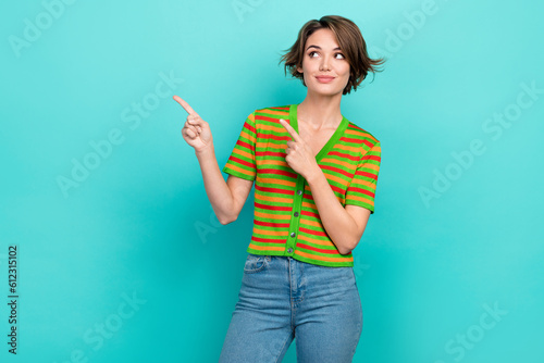 Photo of sweet cheerful woman dressed striped t-shirt looking pointing two fingers empty space isolated turquoise color background © deagreez